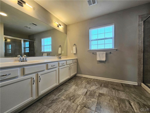 bathroom with double vanity, a stall shower, visible vents, and baseboards