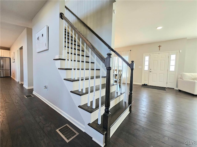 foyer featuring dark wood-style floors, baseboards, and visible vents