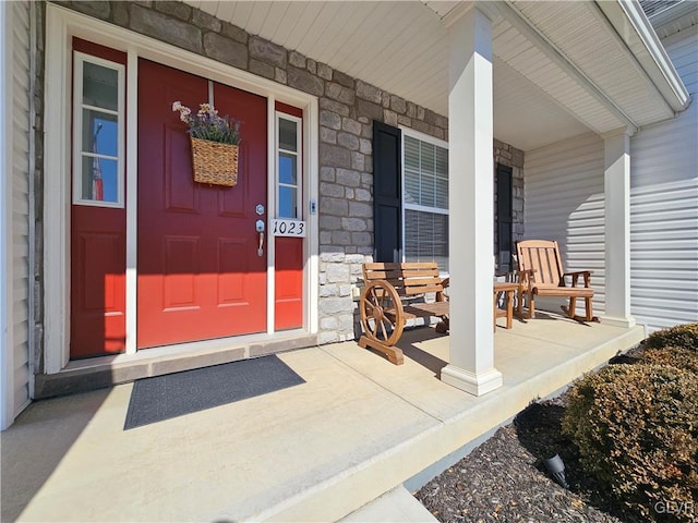 view of exterior entry with stone siding and covered porch