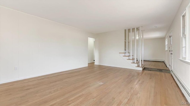 unfurnished living room featuring light wood-type flooring, stairway, and a baseboard radiator