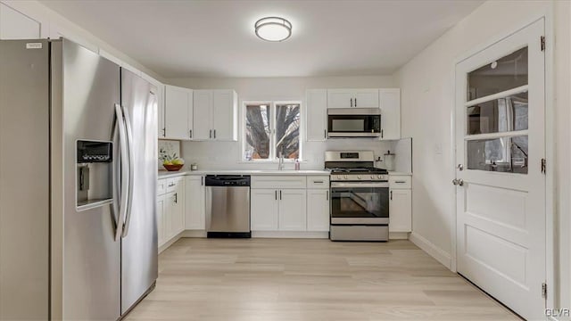 kitchen with stainless steel appliances, tasteful backsplash, light countertops, and white cabinets