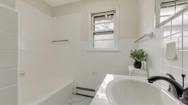 bathroom with a baseboard heating unit, marble finish floor, a sink, and tile walls