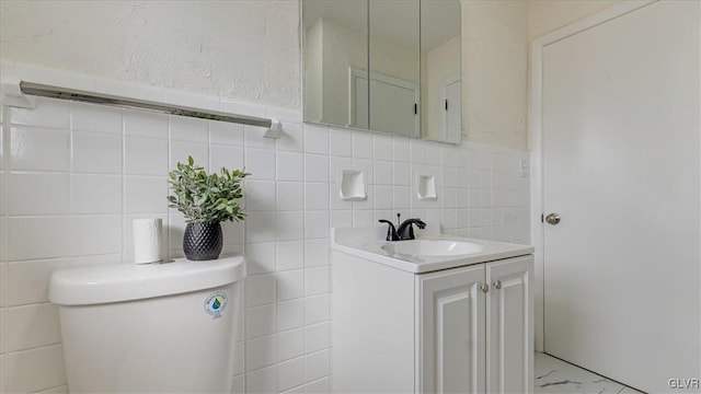 bathroom with toilet, marble finish floor, a textured wall, and vanity