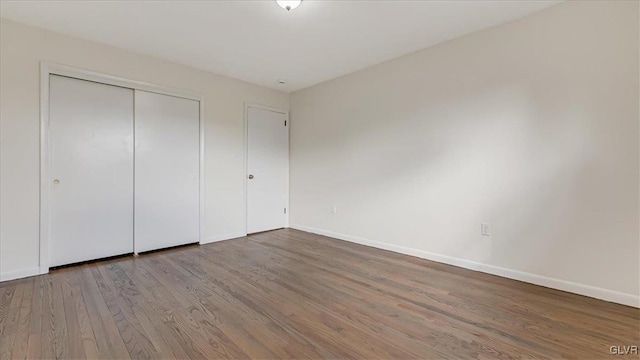 unfurnished bedroom with a closet, wood finished floors, and baseboards