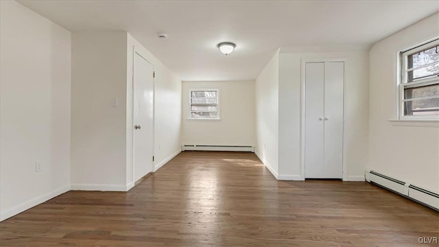 unfurnished bedroom with a baseboard radiator, baseboards, and wood finished floors