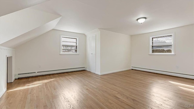 additional living space featuring a baseboard heating unit, plenty of natural light, and light wood-style floors