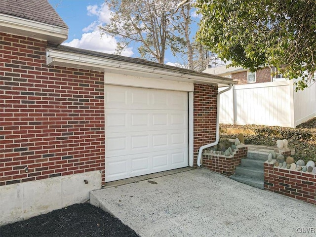 garage featuring concrete driveway and fence