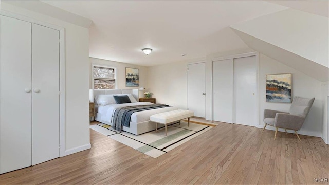 bedroom featuring light wood finished floors and two closets