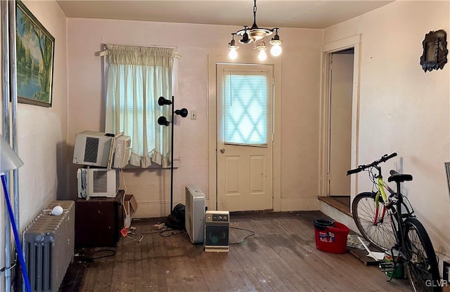 entryway with cooling unit, radiator, hardwood / wood-style floors, and an inviting chandelier