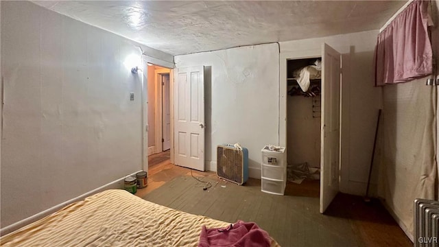 unfurnished bedroom featuring a closet, radiator, and wood-type flooring