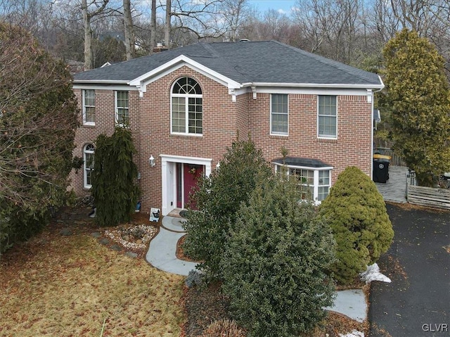 view of front of house featuring aphalt driveway, brick siding, and roof with shingles