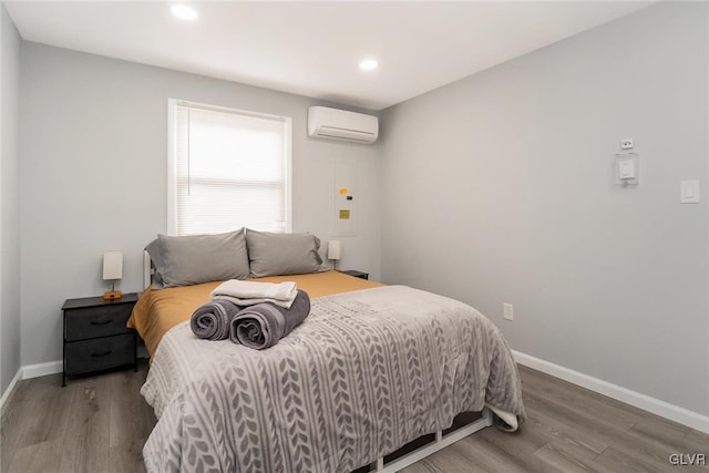 bedroom with recessed lighting, a wall unit AC, wood finished floors, and baseboards