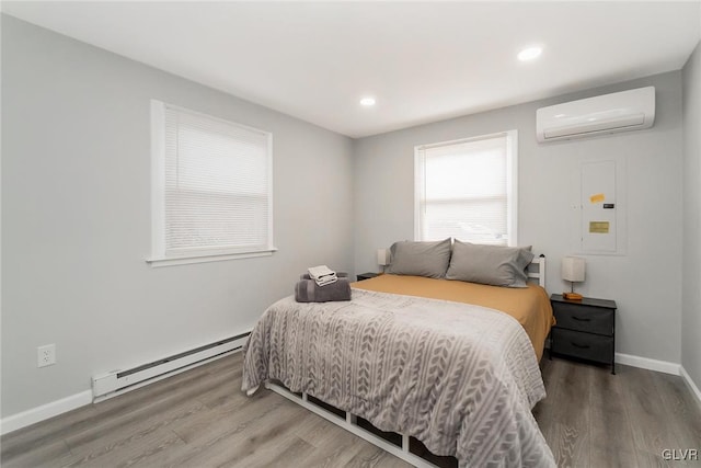 bedroom featuring a baseboard radiator, wood finished floors, baseboards, a wall mounted AC, and electric panel