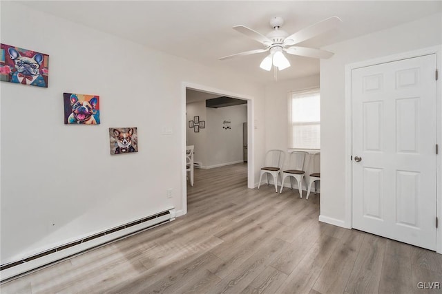 spare room with baseboards, ceiling fan, baseboard heating, and wood finished floors