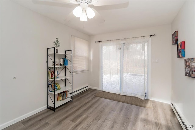 spare room with a baseboard radiator, ceiling fan, baseboards, and wood finished floors