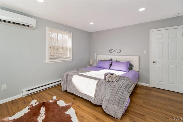 bedroom with a wall unit AC, recessed lighting, a baseboard heating unit, wood finished floors, and baseboards