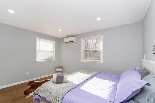 bedroom with recessed lighting, a wall unit AC, wood finished floors, and baseboards