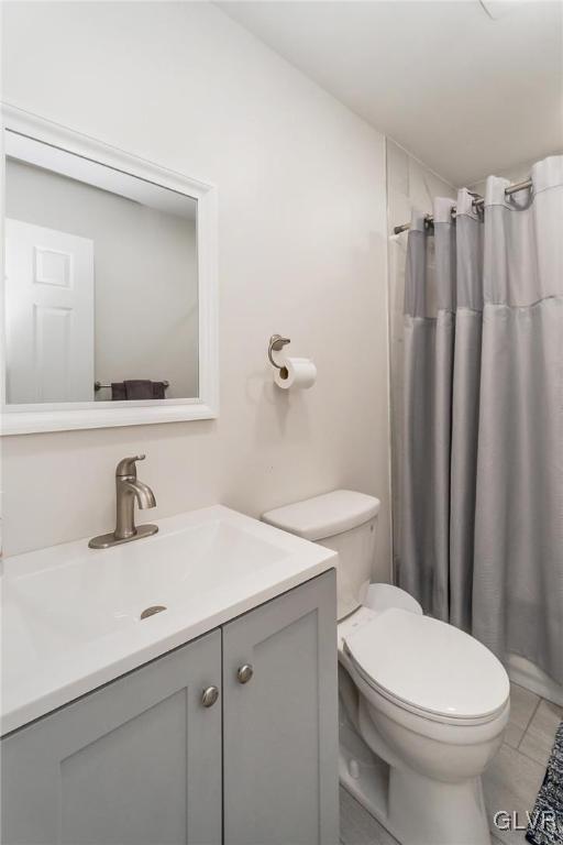 bathroom with toilet, a shower with shower curtain, tile patterned flooring, and vanity