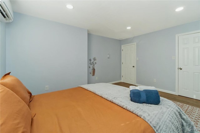 bedroom featuring recessed lighting, an AC wall unit, baseboards, and wood finished floors