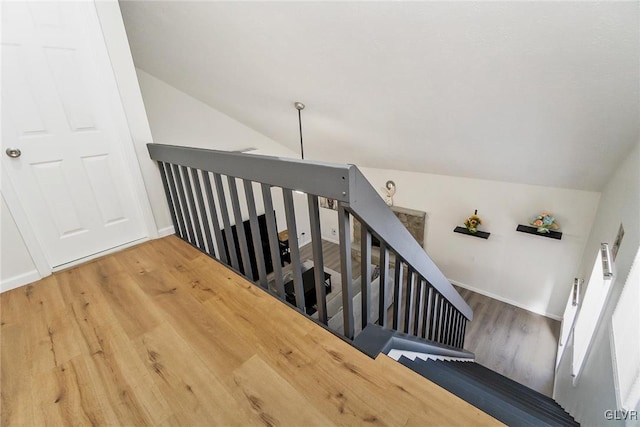 stairs featuring lofted ceiling, wood finished floors, and baseboards