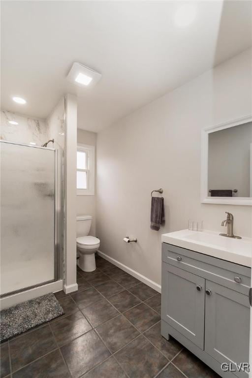 bathroom with toilet, a stall shower, vanity, tile patterned flooring, and baseboards