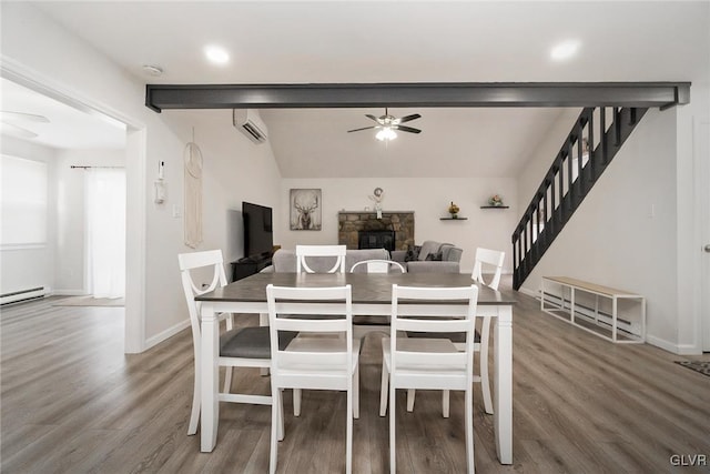 dining room featuring a fireplace, ceiling fan, wood finished floors, a wall mounted air conditioner, and stairs