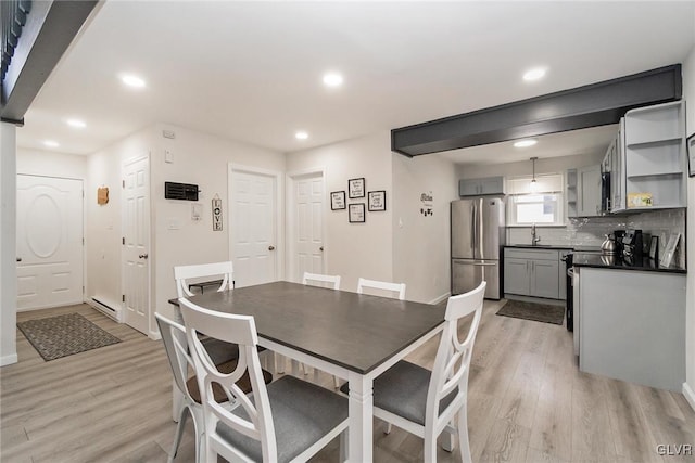 dining room with a baseboard heating unit, light wood finished floors, baseboards, and recessed lighting