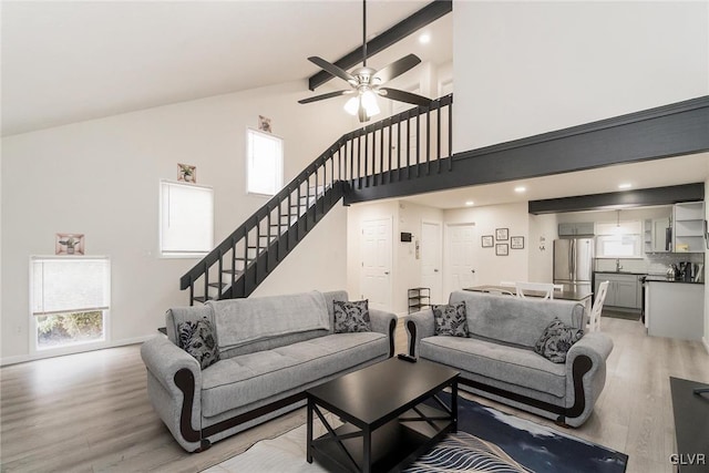 living area with stairs, high vaulted ceiling, light wood-style flooring, and a ceiling fan