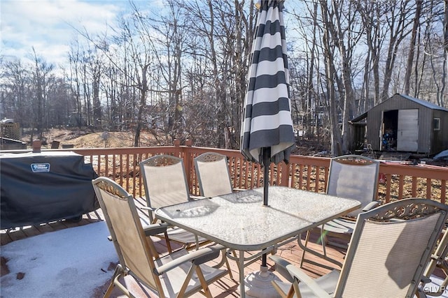 wooden deck featuring grilling area, a storage shed, outdoor dining area, and an outdoor structure