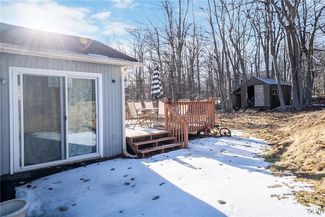 snow covered deck with a storage shed and an outdoor structure