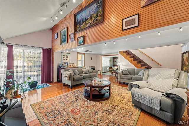 living area with stairs, high vaulted ceiling, wood finished floors, and rail lighting