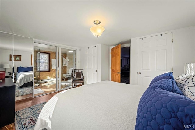 bedroom with dark wood-style floors, access to exterior, and baseboard heating