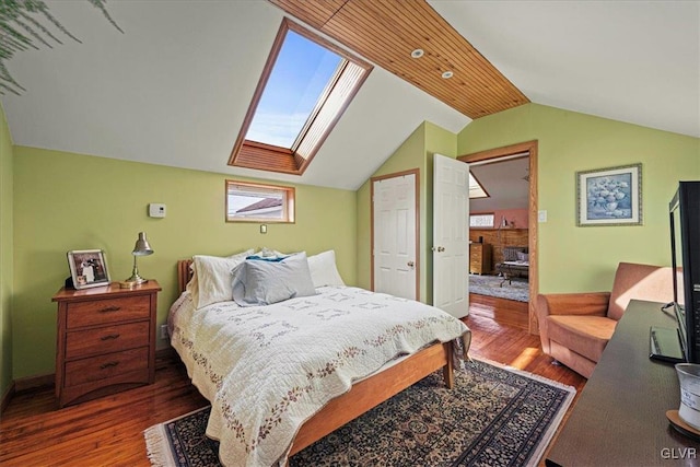 bedroom with lofted ceiling with skylight and wood finished floors