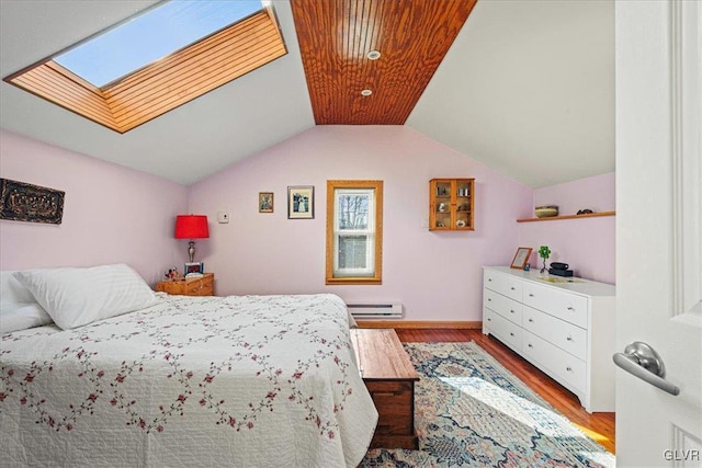 bedroom featuring light wood-style floors, vaulted ceiling with skylight, and baseboard heating