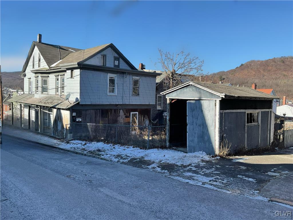 view of front of house featuring an outbuilding, a storage unit, and fence