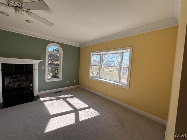 unfurnished living room featuring plenty of natural light, a fireplace, baseboards, and ornamental molding