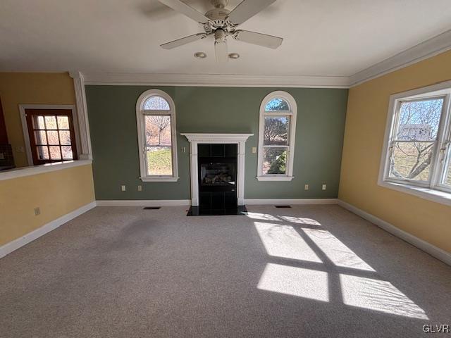 unfurnished living room with crown molding, carpet flooring, a fireplace, and a healthy amount of sunlight