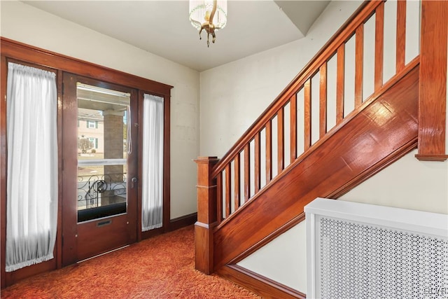 carpeted foyer featuring stairway and plenty of natural light