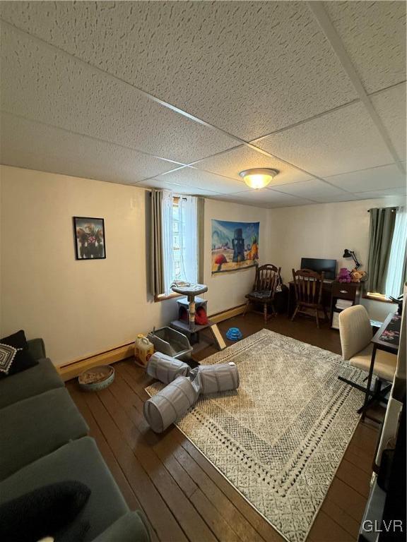 living room with a baseboard radiator, wood-type flooring, baseboards, and a drop ceiling