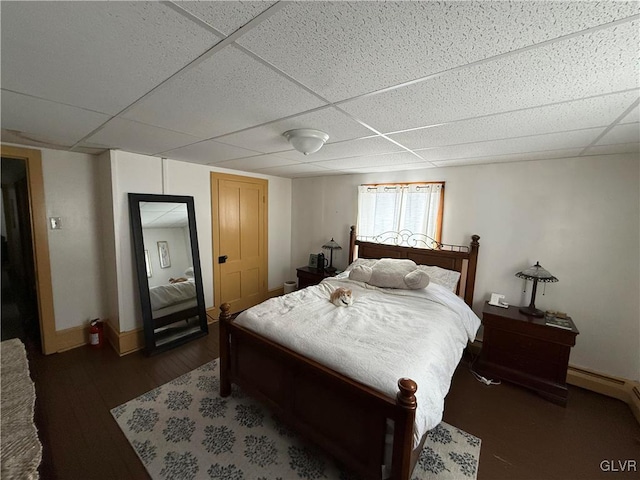 bedroom with a drop ceiling, baseboards, and wood finished floors