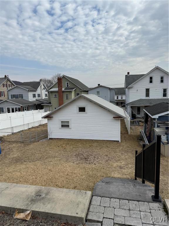 view of home's exterior featuring a residential view, fence, and an outdoor structure