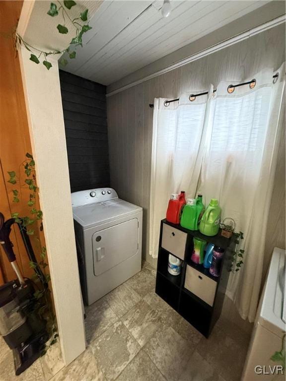 clothes washing area featuring wooden walls and washer / clothes dryer