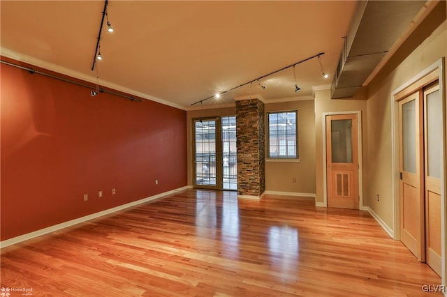 unfurnished room with baseboards, ornamental molding, rail lighting, and light wood-style floors