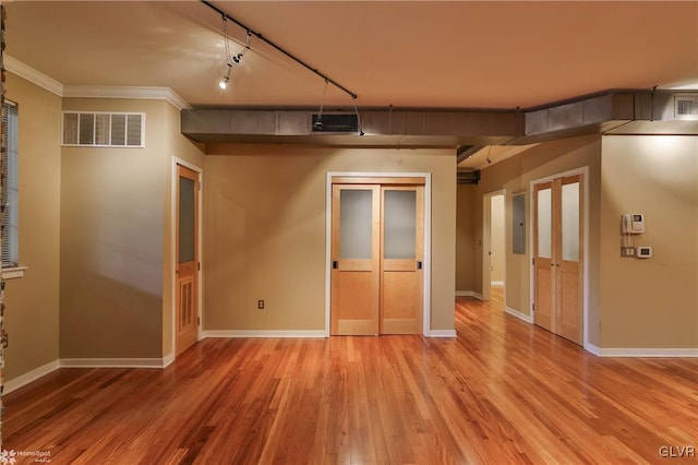 spare room featuring ornamental molding, light wood-type flooring, visible vents, and baseboards