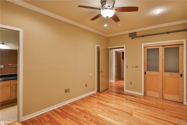 unfurnished bedroom with connected bathroom, visible vents, baseboards, light wood-type flooring, and crown molding