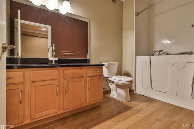 bathroom featuring vanity, a bathtub, wood finished floors, and toilet