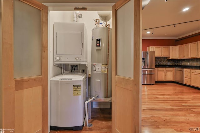 clothes washing area with stacked washer and dryer, light wood-style flooring, electric water heater, crown molding, and a sink