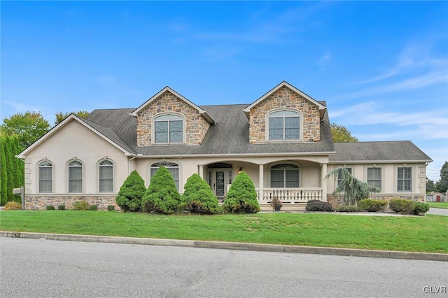 view of front of house with stone siding, a front yard, a porch, and stucco siding