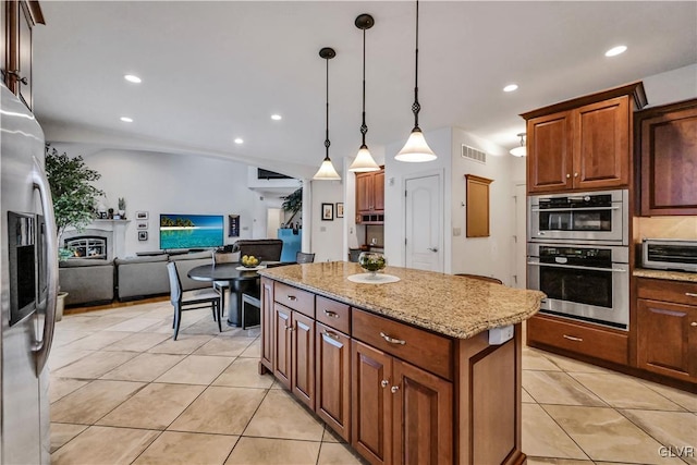 kitchen with visible vents, a kitchen island, decorative light fixtures, stainless steel appliances, and light tile patterned flooring