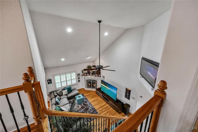 living area featuring a warm lit fireplace, recessed lighting, wood finished floors, a ceiling fan, and vaulted ceiling